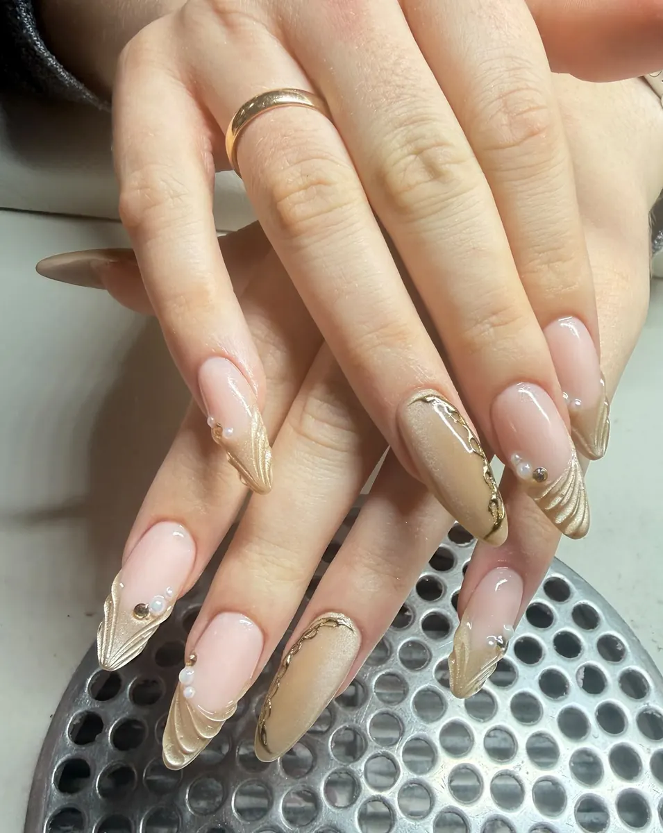 Mandelnägel in Nude mit goldenen Linien und Steinen